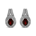 Pair of silver earrings with red gemstones on a white background