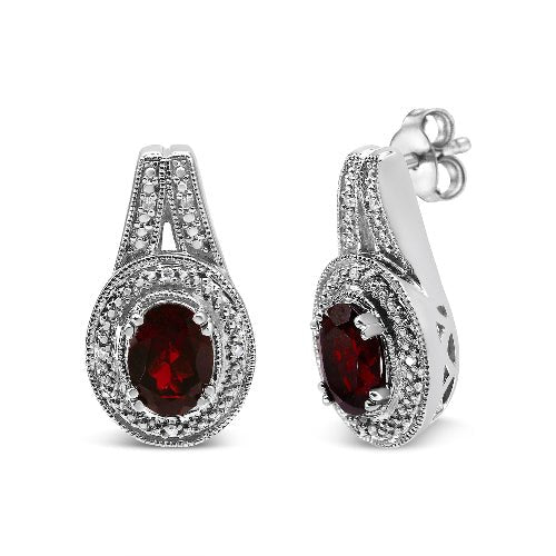 Pair of earrings with red gemstones and silver accents on a white background