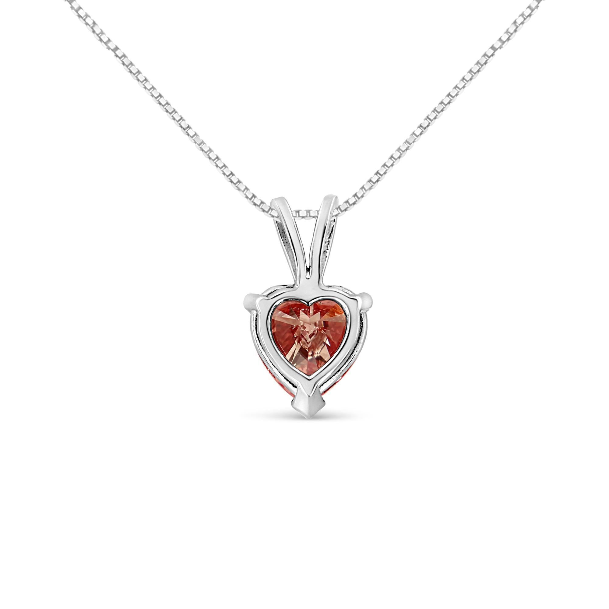 Heart-shaped white gold pendant with a red gemstone on a white background