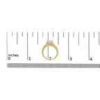 Gold ring with diamond on a white background with a ruler for scale.