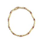 Gold bracelet with embedded red stones on a white background