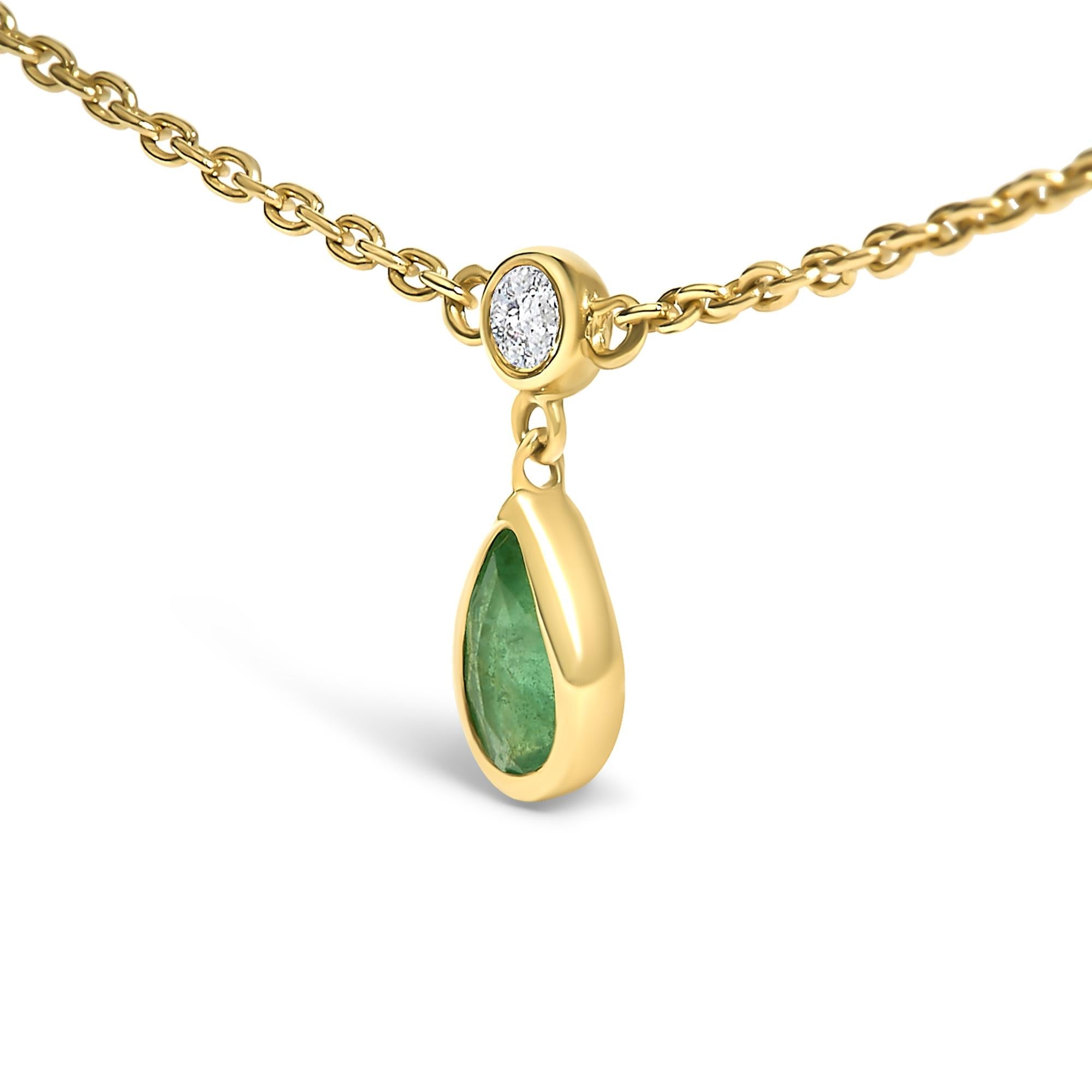 Gold necklace with a green teardrop pendant and diamond charm on a white background
