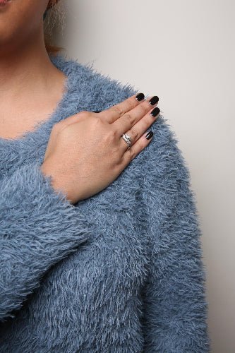 Person wearing a blue fluffy sweater with a neutral background