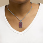 Necklace with a red pendant worn by a person on a beige background