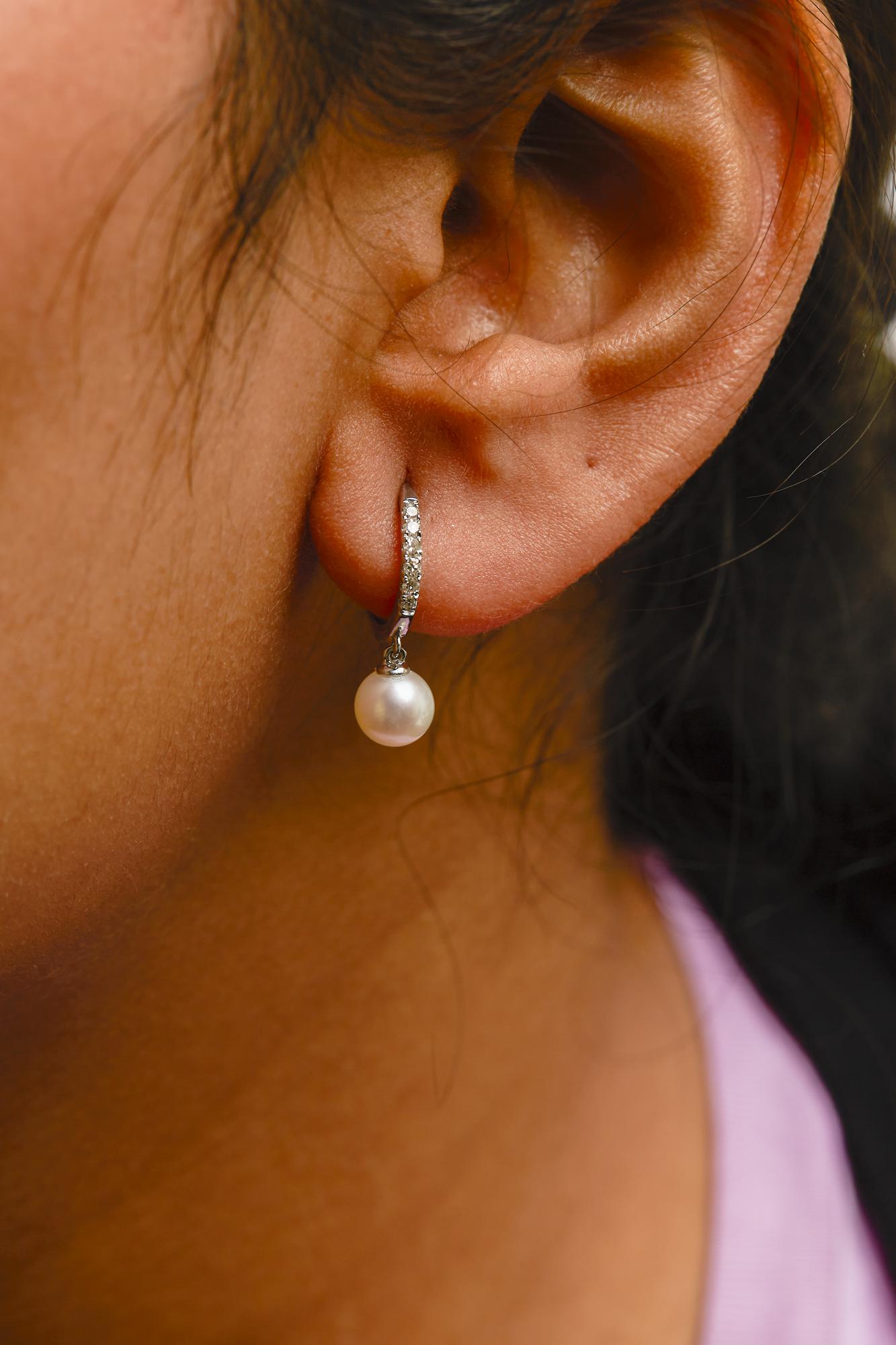 Close-up of an ear wearing a pearl earring with a blurred background