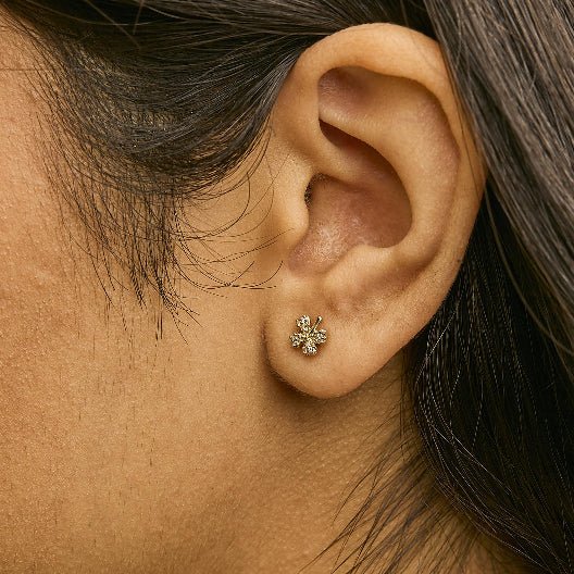 Close-up of an ear wearing a gold earring with dark hair.