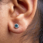 Close-up of an ear with a blue gemstone earring.