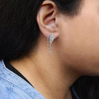 Close-up of a person wearing a silver wing-shaped earring.
