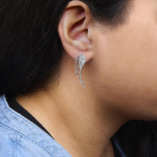 Close-up of a person wearing a silver wing-shaped earring.