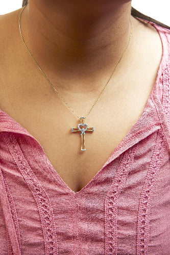 Necklace with a cross pendant worn by a person in a pink top