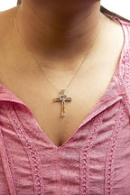 Necklace with a cross pendant worn by a person in a pink top