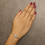 Hand wearing a silver bracelet on a brown background