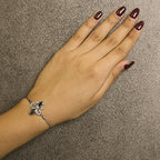 Hand wearing a silver bracelet on a brown background