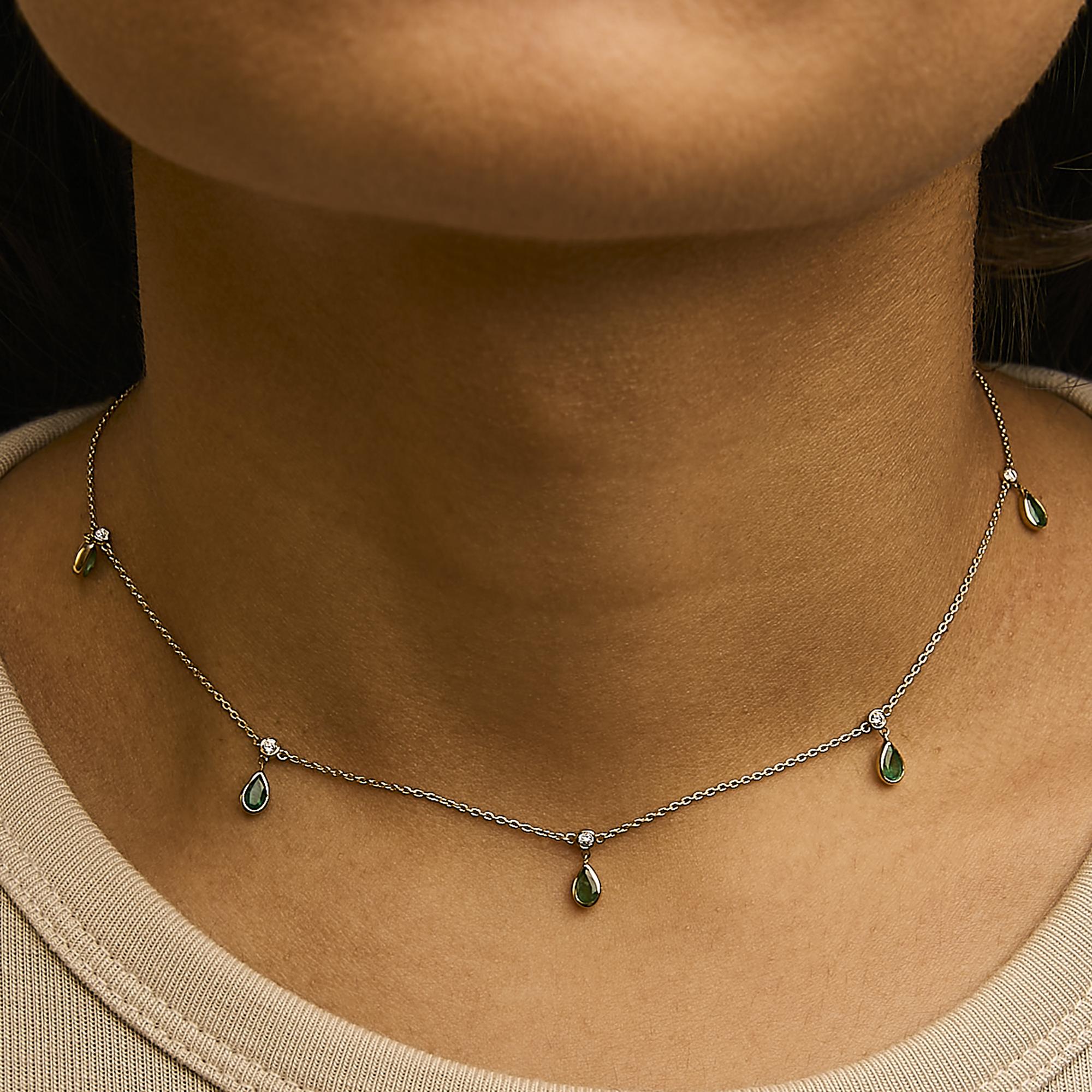 Necklace with green teardrop pendants on a person wearing a beige top.