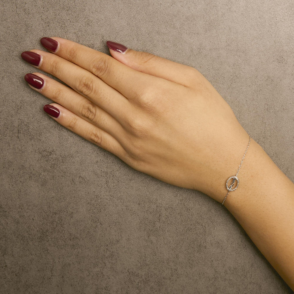 Hand wearing a delicate bracelet on a neutral background