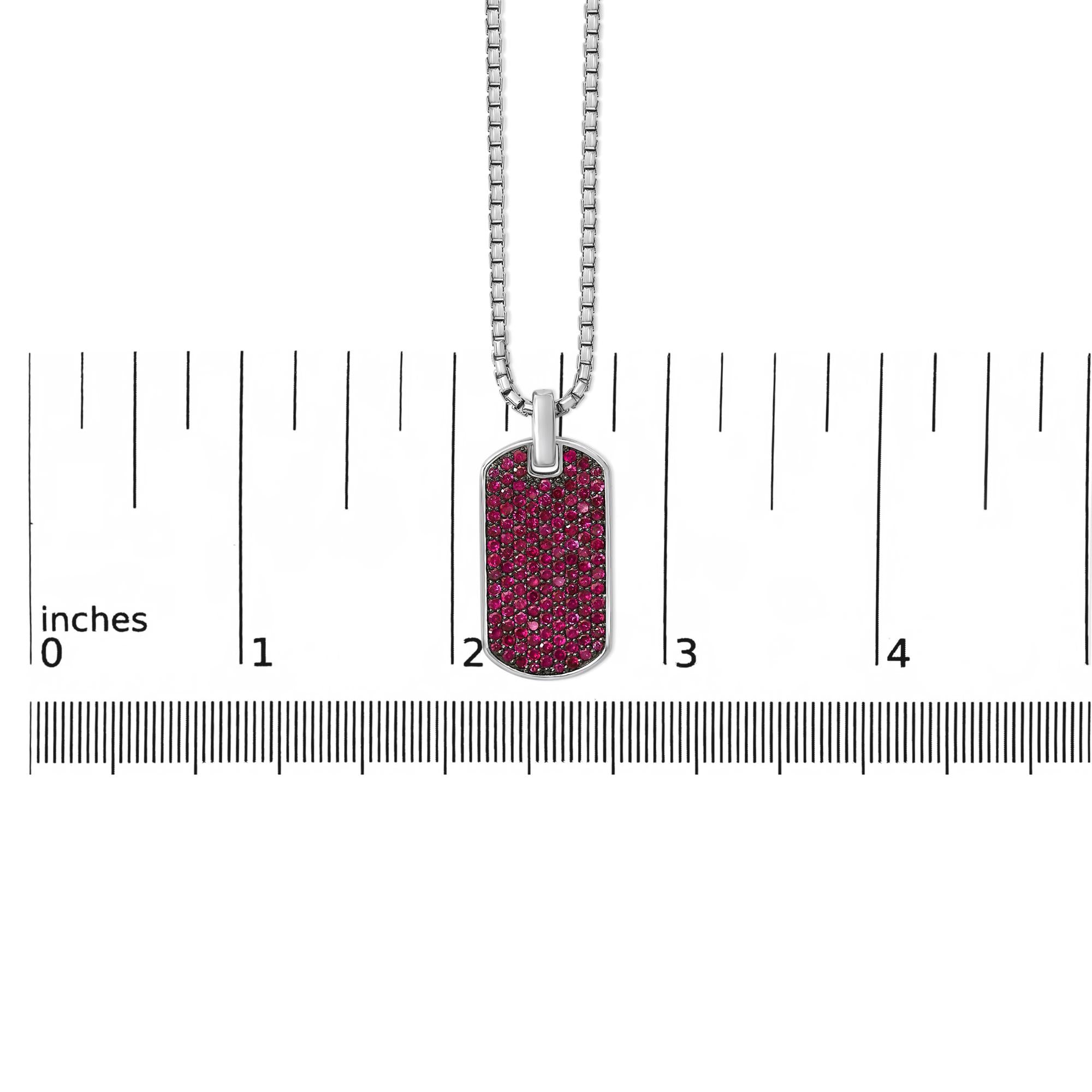 Dog tag pendant with pink glittery design on a chain, shown with a ruler for scale.