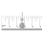 Silver pendant with a green stone on a ruler for scale