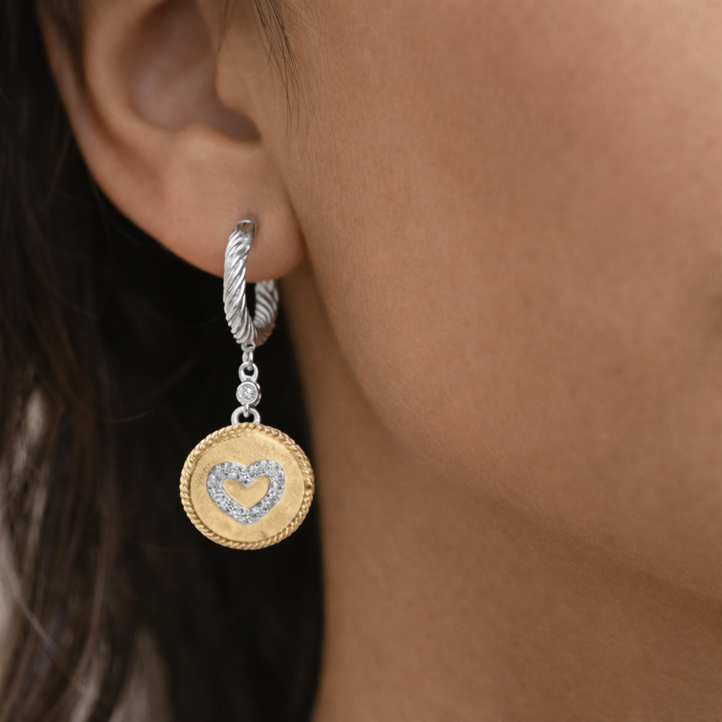 Gold earring with heart-shaped diamond pendant worn by a person