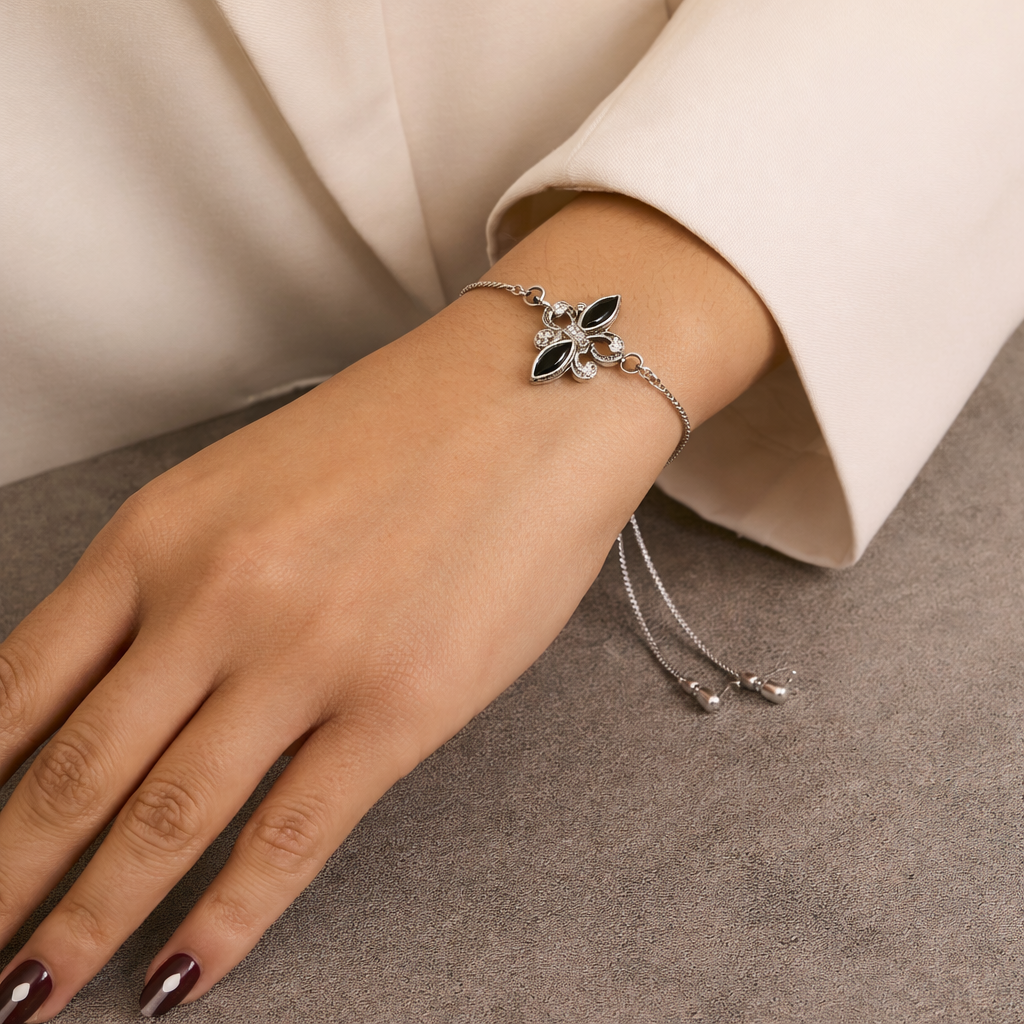 Silver bracelet with black stones on a wrist against a neutral background