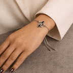 Silver bracelet with black stones on a wrist against a neutral background