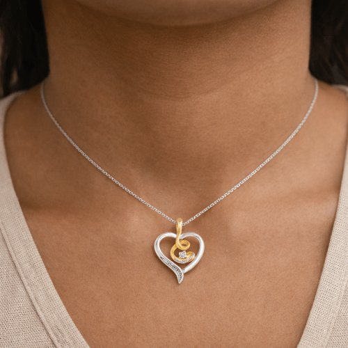 Necklace with a heart-shaped pendant featuring a gold and silver design on a person's neck.