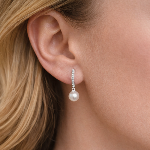 Pearl earring worn by a person with blonde hair.