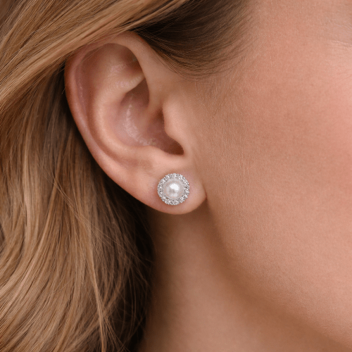 Close-up of an ear wearing a pearl earring with a halo of smaller stones.