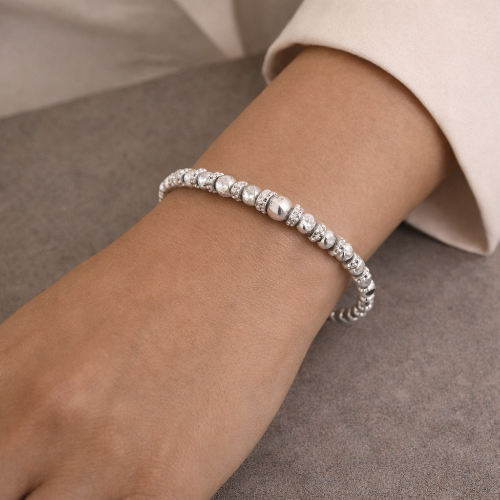 Silver beaded bracelet on a wrist against a neutral background