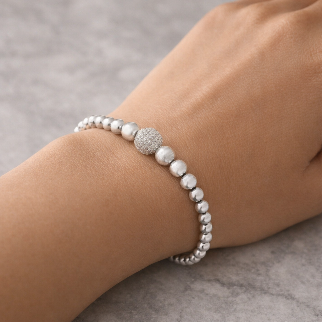 Silver beaded bracelet on a wrist against a neutral background
