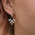 Silver earring with black and orange gemstones worn by a person with brown hair.
