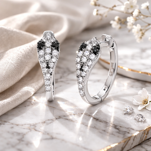 Silver earrings with black and white gemstones on a marble surface with flowers.